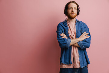 Young ginger bearded man listening music with headphones