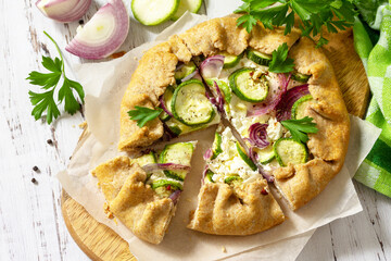 Healthy rye flour baked goods, gluten free, diet food. Galette with zucchini, onions and feta cheese on a wooden table.