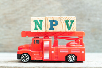 Fire ladder truck hold letter block in word NPV (Abbreviation of net present value) on wood background