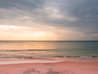 Fototapeta na wymiar adstract color of pink beach in golden sunset at the beach. dramatic gray cloudy sky above sea water.