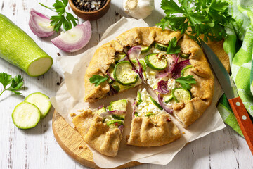 Healthy rye flour baked goods, gluten free, diet food. Galette with zucchini, onions and feta cheese on a wooden table.
