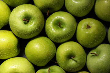 Ripe green apples with water drops as background, top view