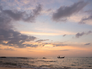 dramatic clouds pastel sky at tropical sea. small fishing boat floating on water.