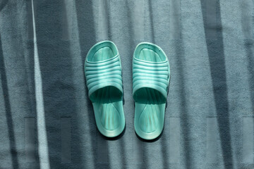 Green indoor plastic sandals on blue carpet.