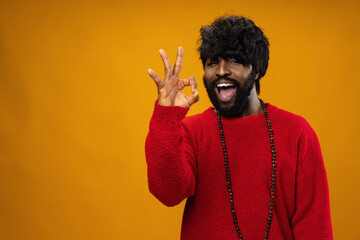 Black man showing ok sign against yellow background