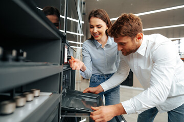 Young couple choosing new electric oven in hypermarket