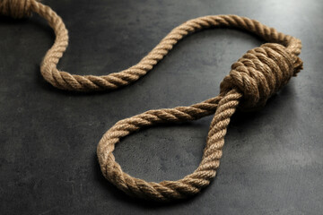 Rope noose with knot on grey table, closeup