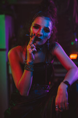 girl in a futuristic cyberpunk costume smokes a cigarette with a neon light in the garage. Steampunk style