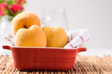 Yellow peaches fruit in a red bowl, Tropical juicy and sweet fruit	