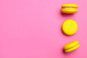 Delicious yellow macarons on pink background, flat lay. Space for text