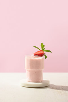 Indian strawberry lassi or milkshake on pink modern paper background. Vertical format.