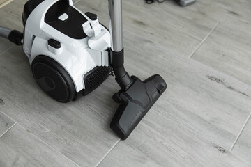 Bagless cyclone vacuum cleaner on a grey tile. Electrical apparatus that by means of suction collects dust and small particles from floors and other surfaces.