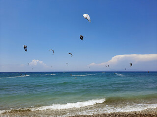 Kiteboarders catch the wind in the Rhodos, Greece. Aegean Sea. Extreme water sport. Group of kiteboarding is flying in the blue sky by the wind blow.