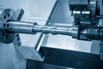 The  CNC lathe machine cutting the metal shaft parts. The hi-technology metal working processing by CNC turning machine .