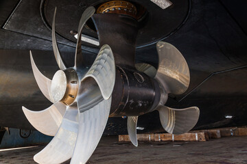 The bottom of a ship supported in dry dock with azimuth propulsion and twin propellers aft. - obrazy, fototapety, plakaty