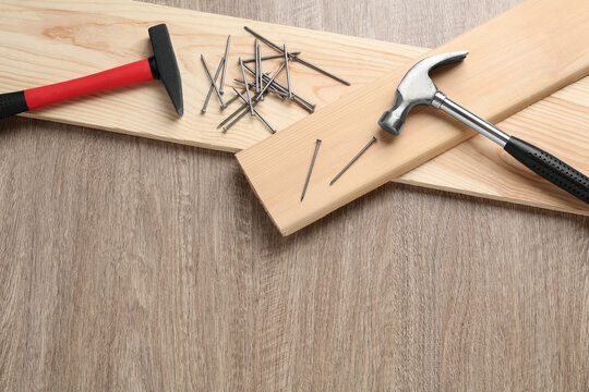 Hammers, metal nails and planks on wooden table, flat lay. Space for text