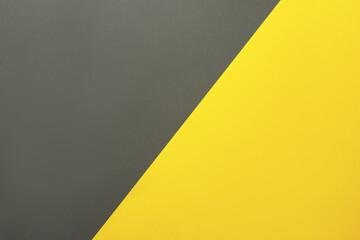 Background of two colors. Yellow and gray colored paper sheets divided diagonally. Flat lay, top...
