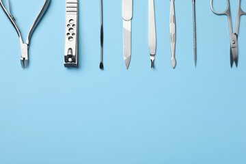 Set of manicure tools on light blue background, flat lay. Space for text - obrazy, fototapety, plakaty