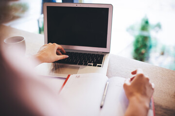 Fototapeta premium Woman using laptop sitting at table with notebook