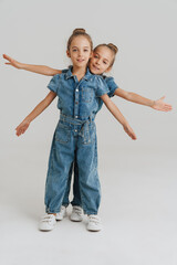 Blonde two girls dressed overalls gesturing while making fun together