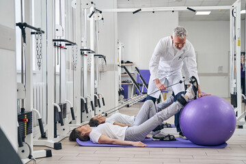 Patient performing a strength training exercise assisted by a kinesiologist