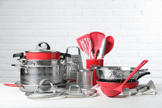 Set of clean kitchenware on white table against brick wall