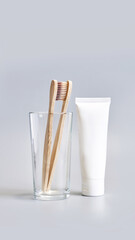 Ecology toothbrush on grey background. Brush in glass. Sustainable mouth product. Zero waste lifestyle. Organic accessory. Dental health at home. Biodegradable recycle. Toothpaste