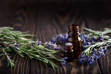 Rosemary and lavender essential oils in dark glass bottles on wood