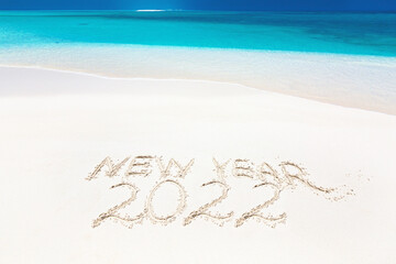 Inscription word NEW YEAR and numbers 2022 on sandy beach