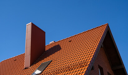 Red corrugated metal profile roof installed on a modern house. The roof of corrugated sheet. Roofing of metal profile wavy shape. Modern roof made of metal. Metal roofing.