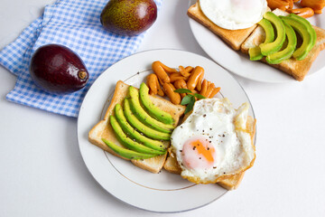 Avocado Sandwich with Fried Egg - sliced avocado and egg on bread and mini sausage for healthy breakfast.