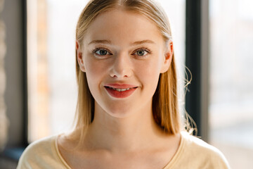 Young blonde white woman smiling and looking at camera indoors
