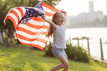 Patriotic holiday. Happy family, mother and daughter with American flag outdoors on sunset. USA...