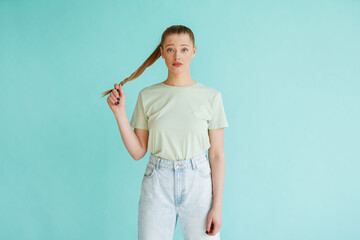 Young blonde white woman frowning while holding her hair