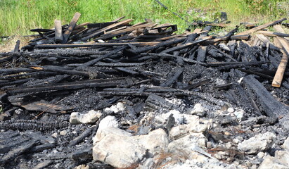 A pile of burnt and charred planks on the grass