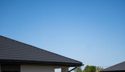 Brown corrugated metal profile roof installed on a modern house. The roof of corrugated sheet. Roofing of metal profile wavy shape. Modern roof made of metal. Metal roofing.