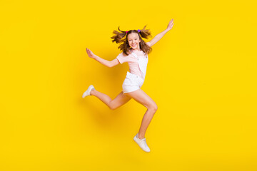 Fototapeta na wymiar Full length body size view of attractive cheerful girl jumping having fun running isolated over bright yellow color background