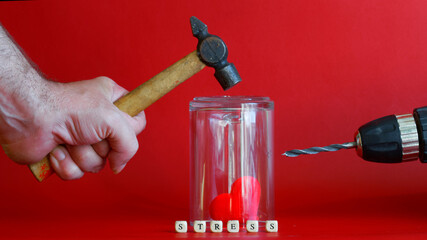 Inscription stress and red heart under glass protective flask next to hammer and drill. The concept...