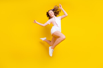 Fototapeta na wymiar Full length body size photo schoolgirl jumping high carefree isolated bright yellow color background
