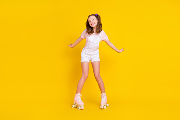 Fototapeta na wymiar Full length body size view of attractive cheerful girl riding skates practicing having fun isolated over bright yellow color background