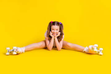 Full length body size photo schoolgirl wearing rollers doing stretching exercises isolated bright yellow color background - obrazy, fototapety, plakaty