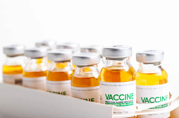 Vials of coronavirus medicine are in packaging on a white background. Vaccine test concept in a laboratory, macro