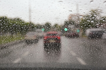 Blurred view of road through wet car window. Rainy weather