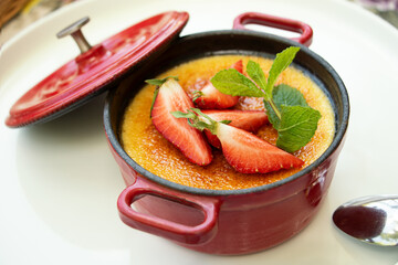 Top view photography of the dessert creme brulee decorated with fresh peppermint and strawberry.Restaurant setting.