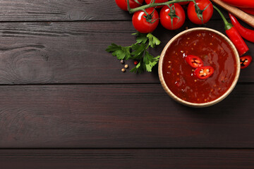 Spicy chili sauce and ingredients on wooden table, flat lay. Space for text