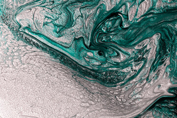 Beautiful shimmer turquoise and silver stains of liquid nail polish with bubbly texture,looks like ocean wave.Stripy paint texture.Nail lacquer flow modern backdrop. Minimalism concept.Copy space.