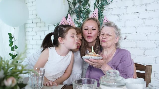 Celebration and family concept. Four woman generation celebrate senior woman 85th birthday, grandmother holds cake and blowing out candle all together. Female family enjoy, respect and warm relation