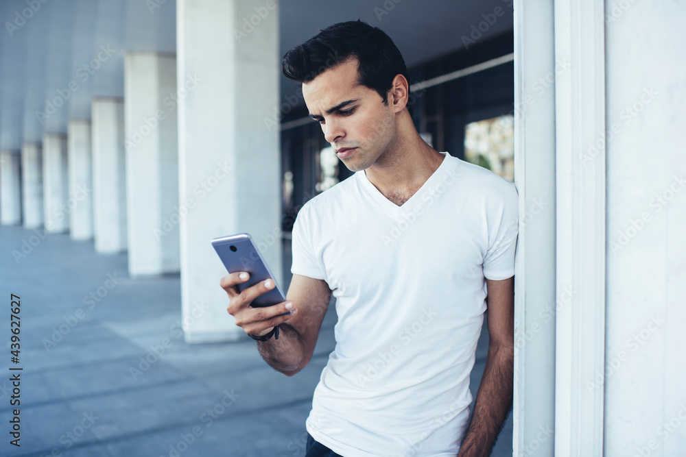 Poster young hipster guy in casual clothes connecting to wireless for chatting and messaging in social medi