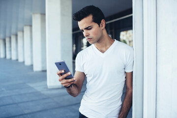 Young hipster guy in casual clothes connecting to wireless for chatting and messaging in social...