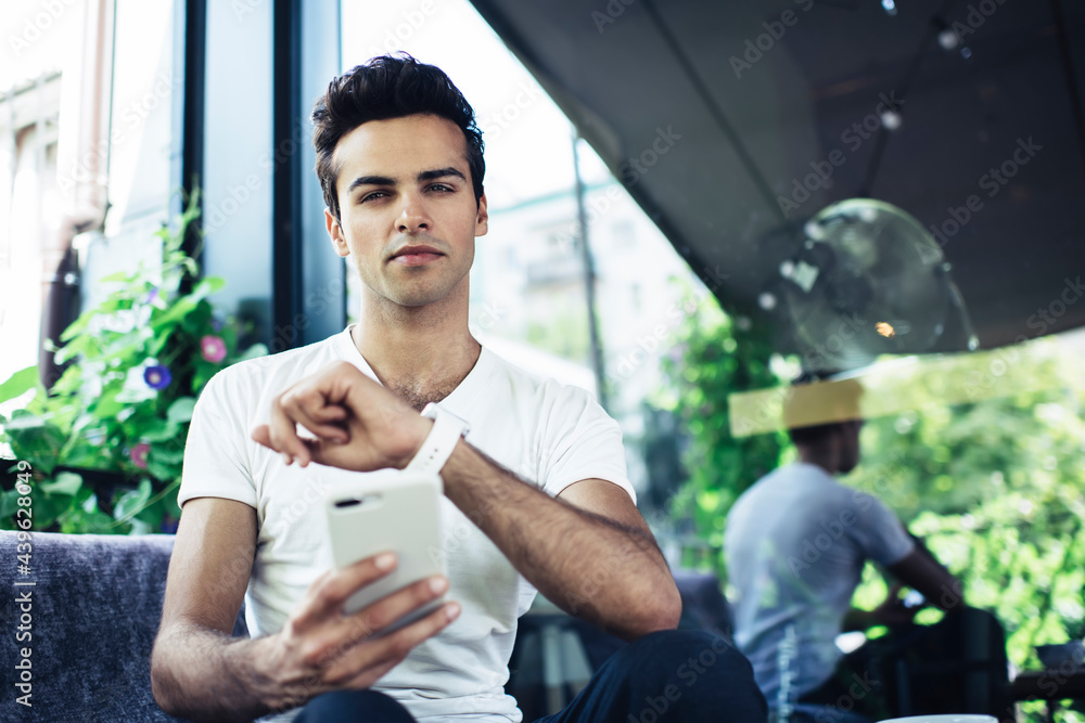 Poster portrait of millennial hipster guy with digital cellphone gadget looking at camera while checking ti